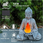 Buddha statue with solar panel and candle, surrounded by greenery
