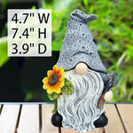 Gnome figurine with a sunflower, measurements displayed, on a wooden surface with a blurred green background.