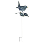 Decorative metal bird on a branch with a stake against a white background