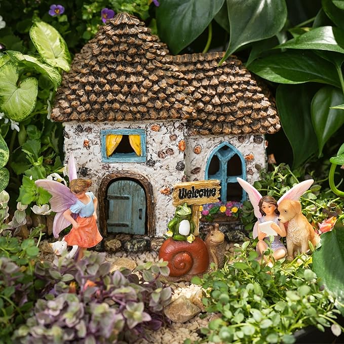 Miniature fairy house with fairies and a dog in a garden setting