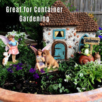 Fairy garden with miniature house, fairies, and animals in a container garden setting.