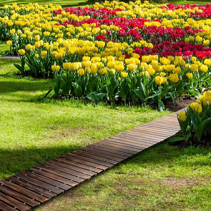 Wooden pathway leading through a garden with rows of yellow and red tulips.