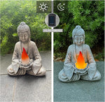 Solar-powered Buddha statue with flame-like light on a garden path.