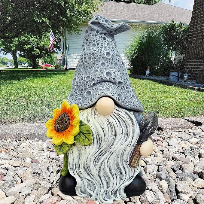 Gnome figurine with a sunflower on a pebble path in a garden setting