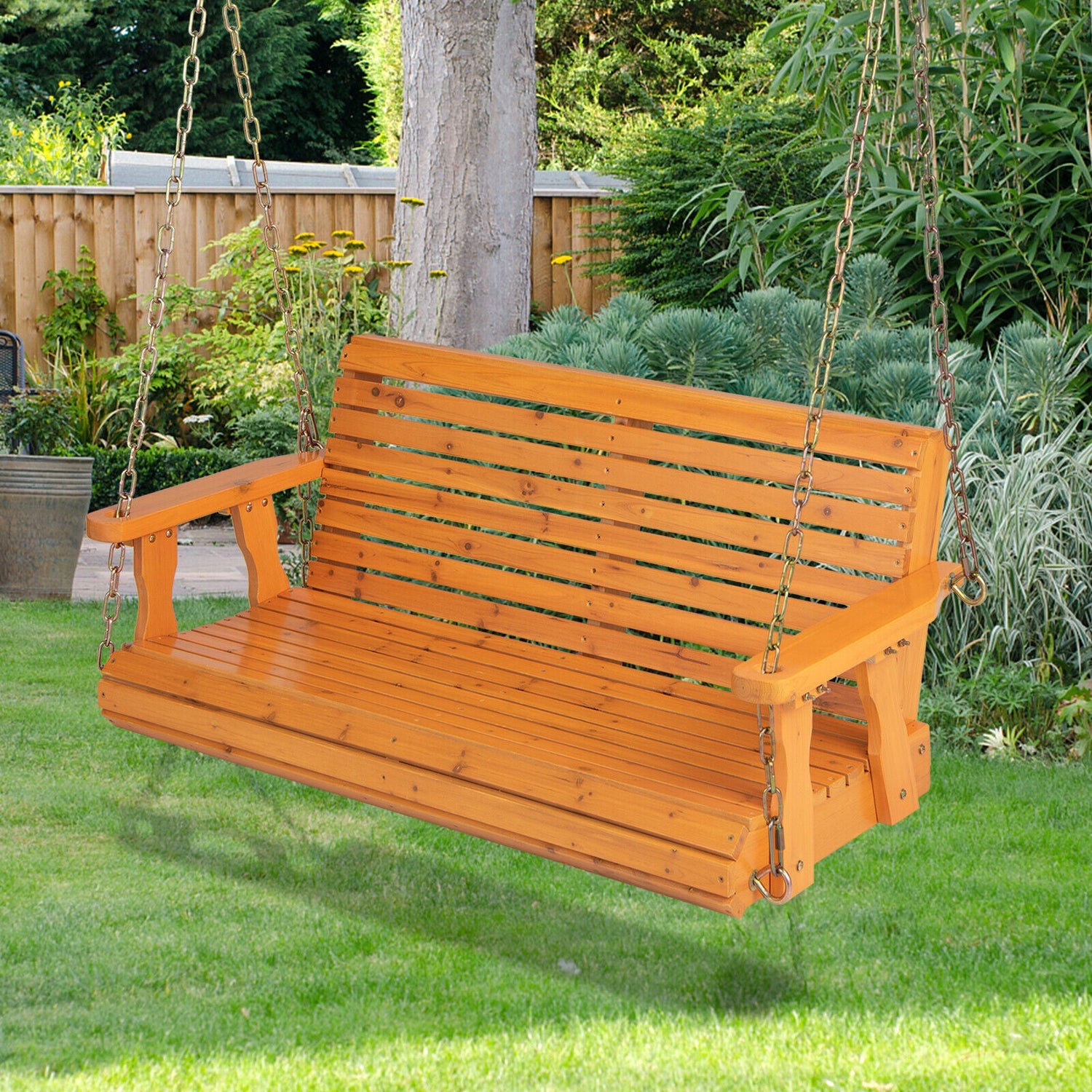 Wooden swing in a garden setting with greenery and a wooden fence.