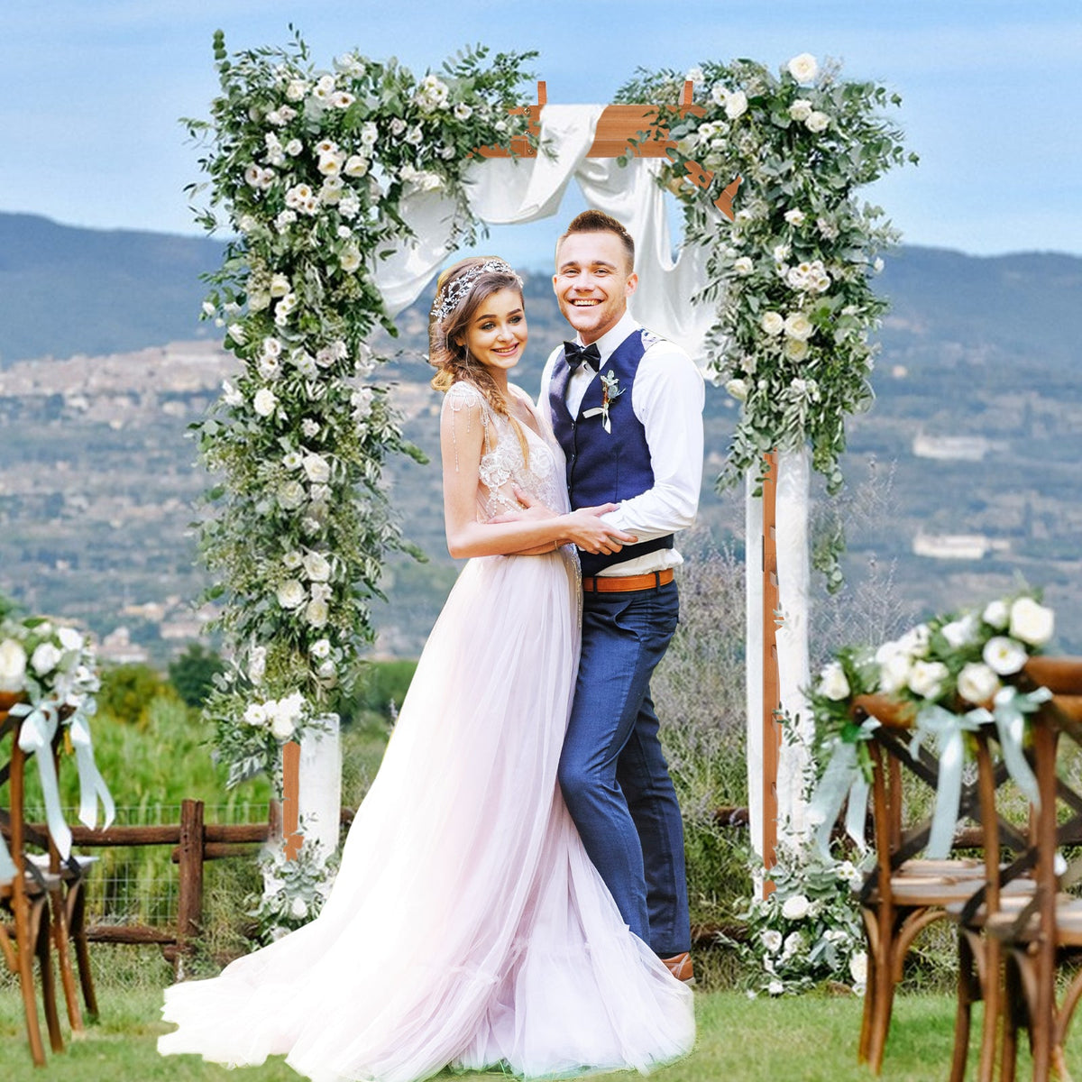 Couple standing under a floral archway with a scenic background