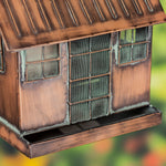 Bronze-colored bird feeder with grid-like design on a blurred natural background