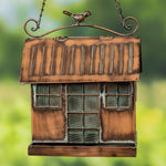 Bronze birdhouse with a bird perched on top against a blurred green background