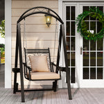 Decorative outdoor swing with beige cushion on a wooden deck, featuring a wreath on a door in the background.