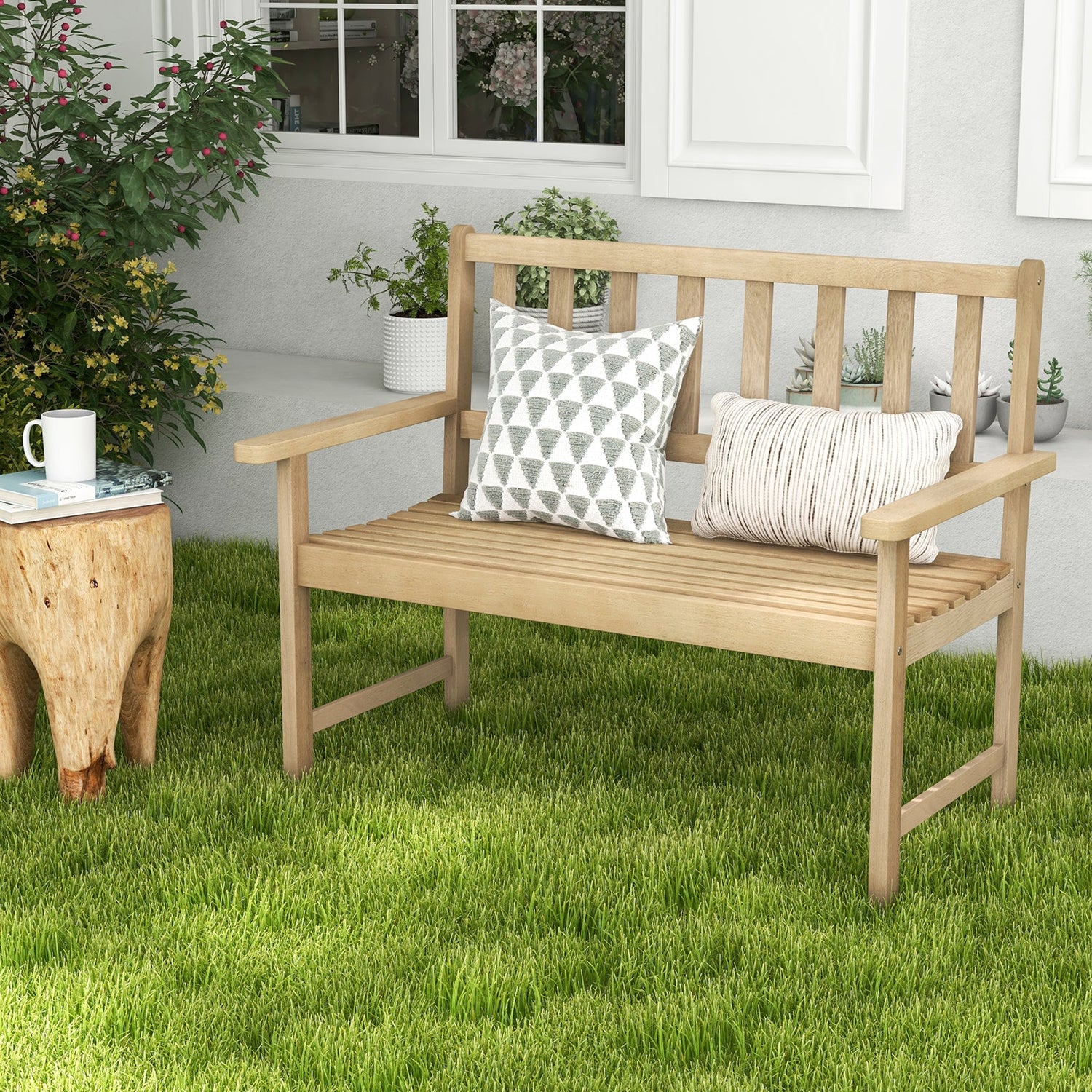 Wooden bench with decorative pillows on a grassy area, with a cup and plant nearby.