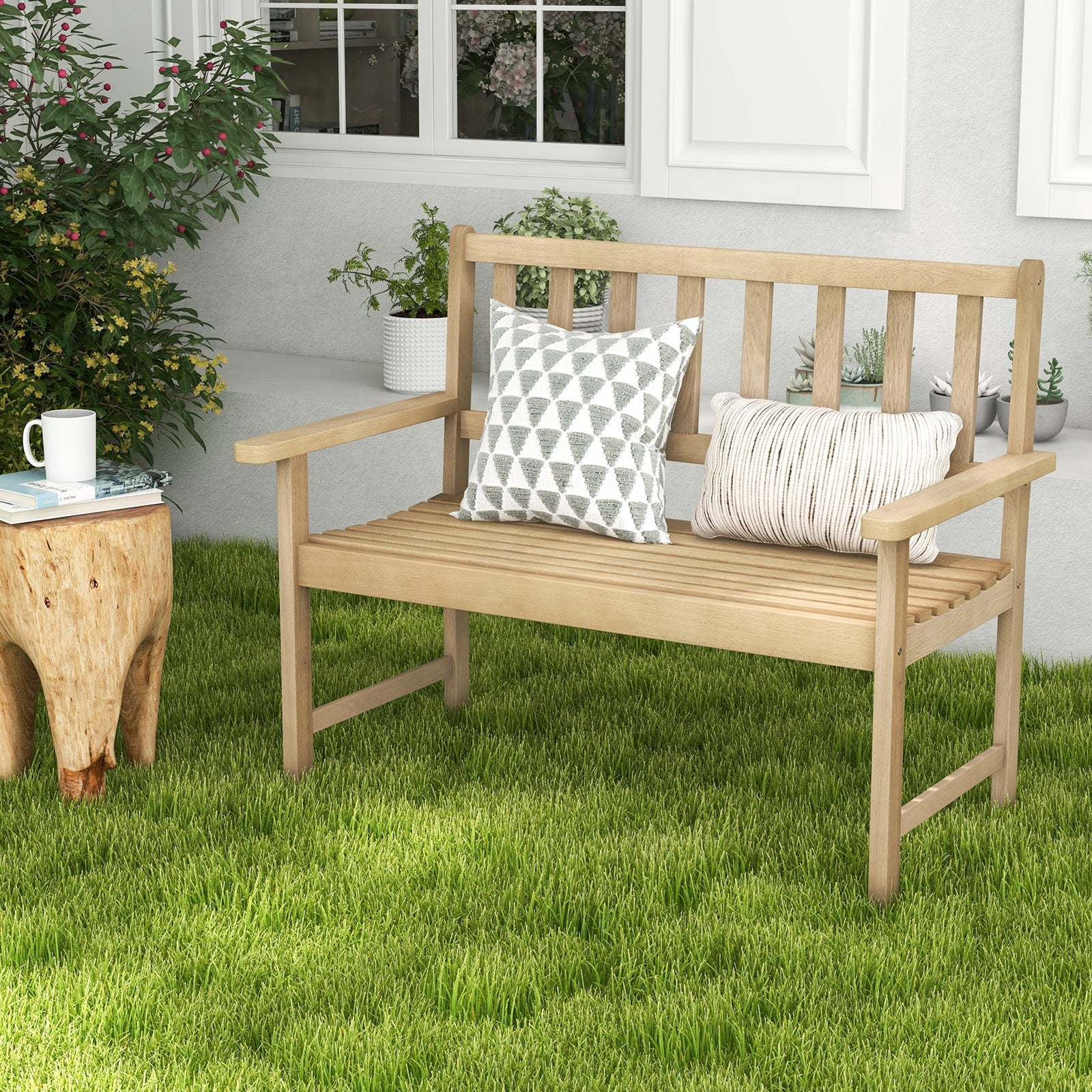 Wooden bench with decorative pillows on a grassy area, with a cup and plant nearby.