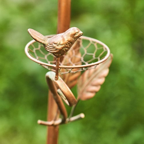 Metal garden stake with a bird design against a green background