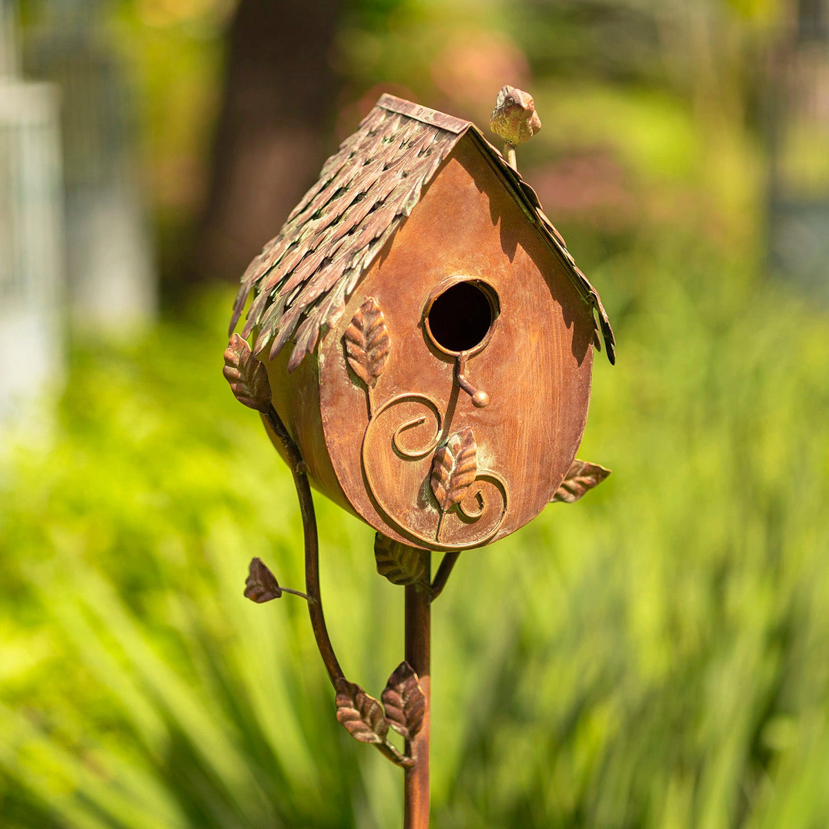 Decorative birdhouse on a stand with a blurred green background