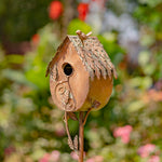 Decorative birdhouse on a stand with a blurred garden background