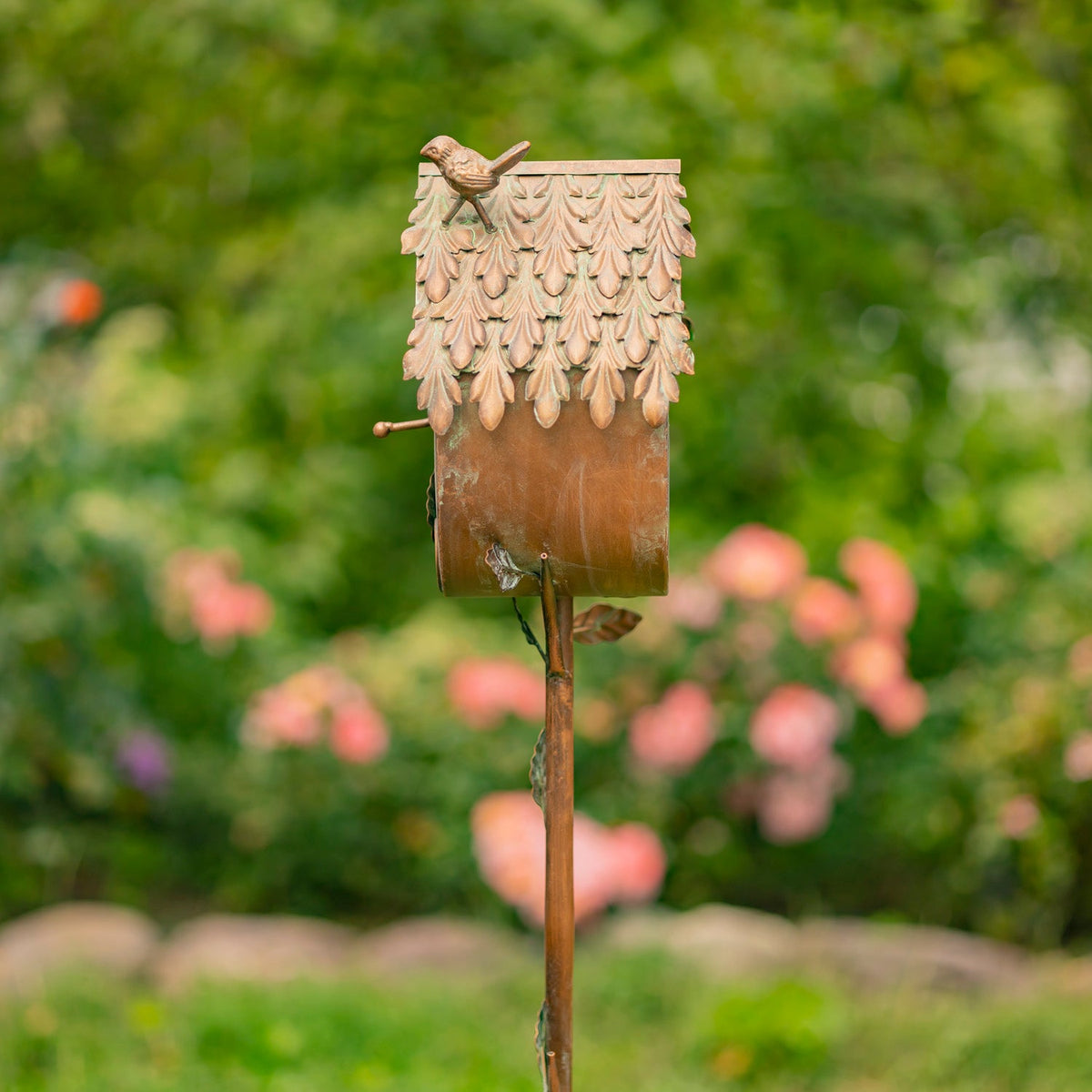 Decorative birdhouse on a stick with a blurred garden background