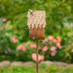 Decorative birdhouse on a stick with a blurred garden background