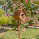 Decorative birdhouse on a stand with a garden background