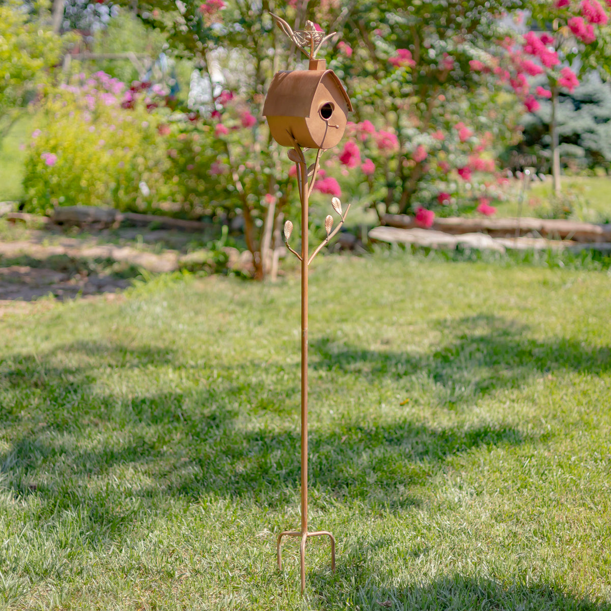 Decorative garden stake with a birdhouse on a grassy lawn