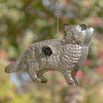 Metallic cat-shaped bird feeder hanging outdoors with a blurred natural background