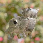 Metallic cat-shaped birdhouse hanging against a blurred natural background