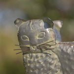 Close-up of a stone sculpture of a cat's head with a blurred natural background