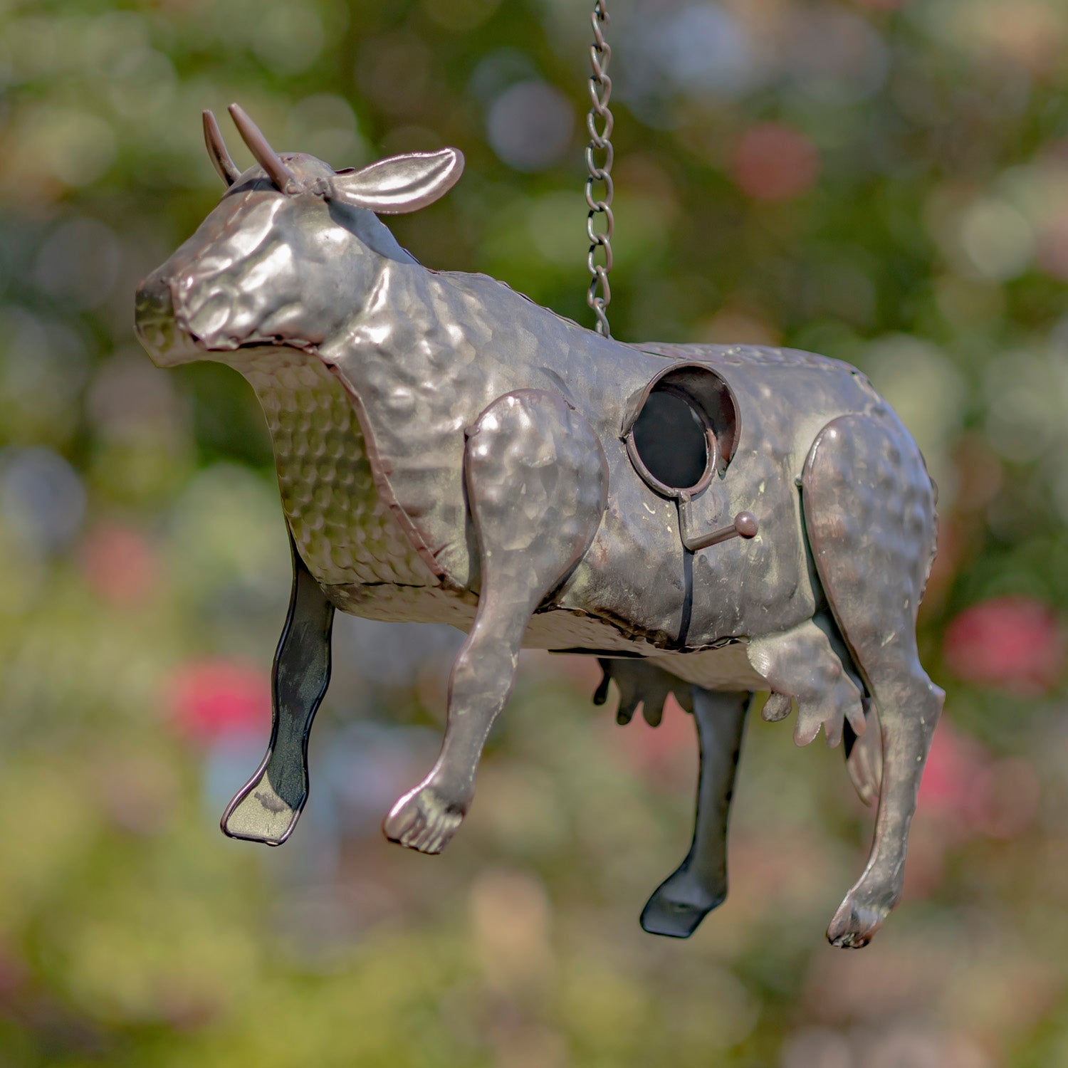 Metallic donkey-shaped object hanging against a blurred natural background