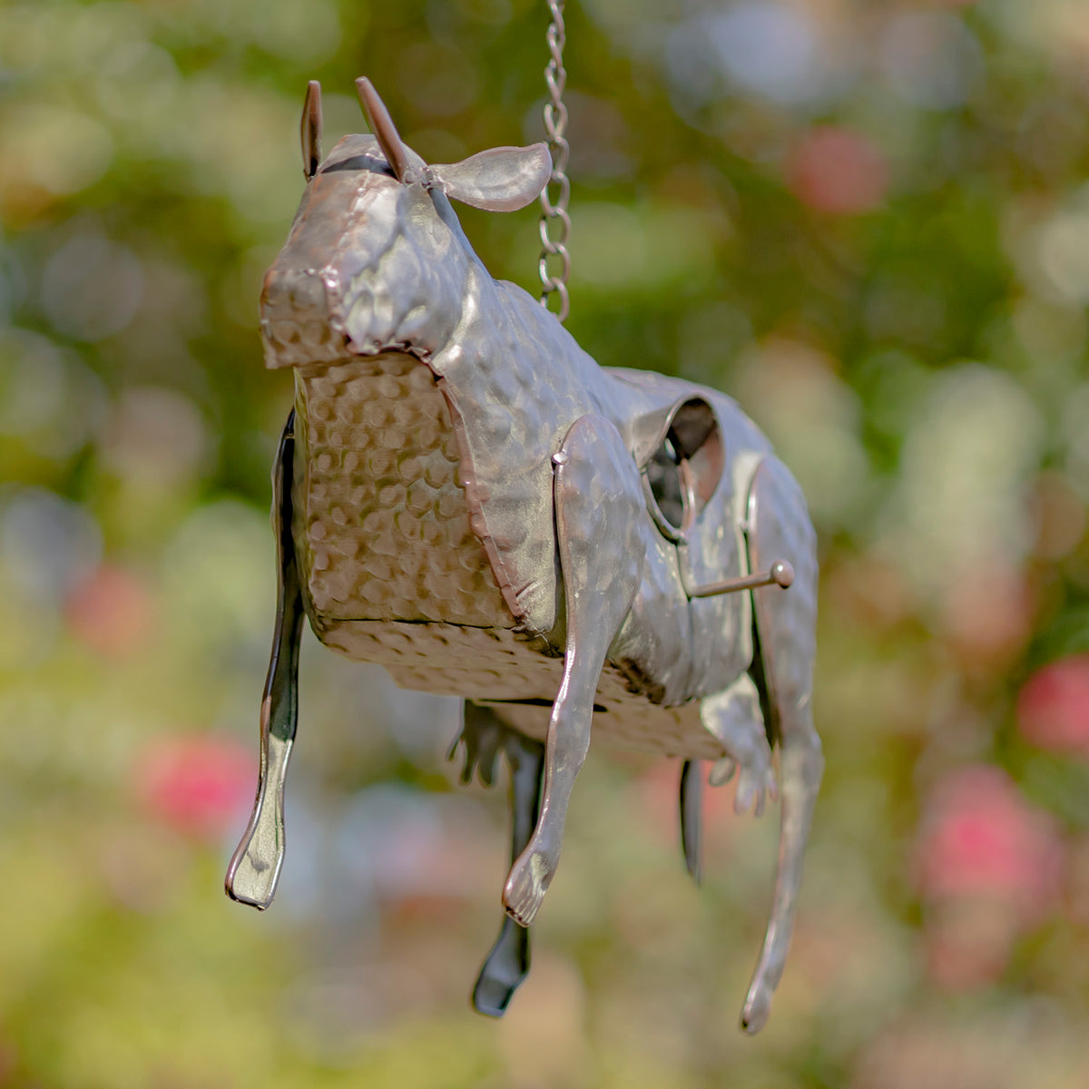 Metallic bird-shaped ornament hanging against a blurred natural background