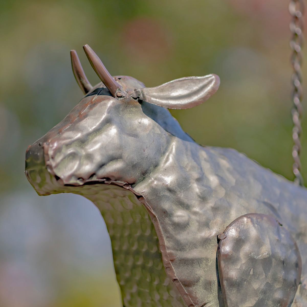 Metallic sculpture of a bull with a blurred natural background
