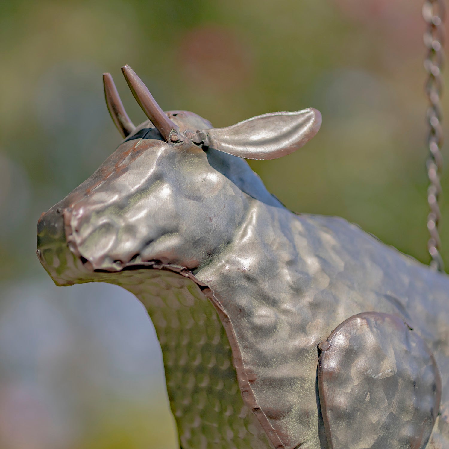 Metallic sculpture of a bull with a blurred natural background
