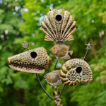 Decorative metal sculpture of seashells with fish on a green leafy background