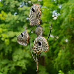 Decorative shell sculpture on a branch with a blurred green foliage background