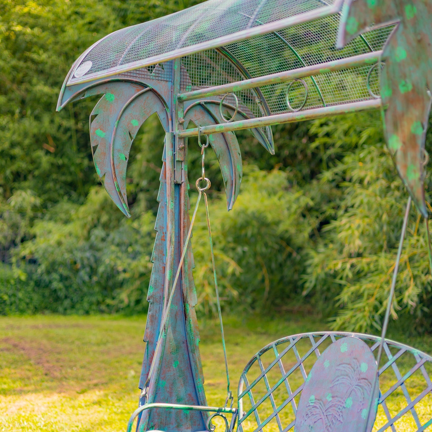 Metallic dragon sculpture in a garden setting with greenery in the background