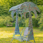 Metal swing with palm tree design in a garden setting