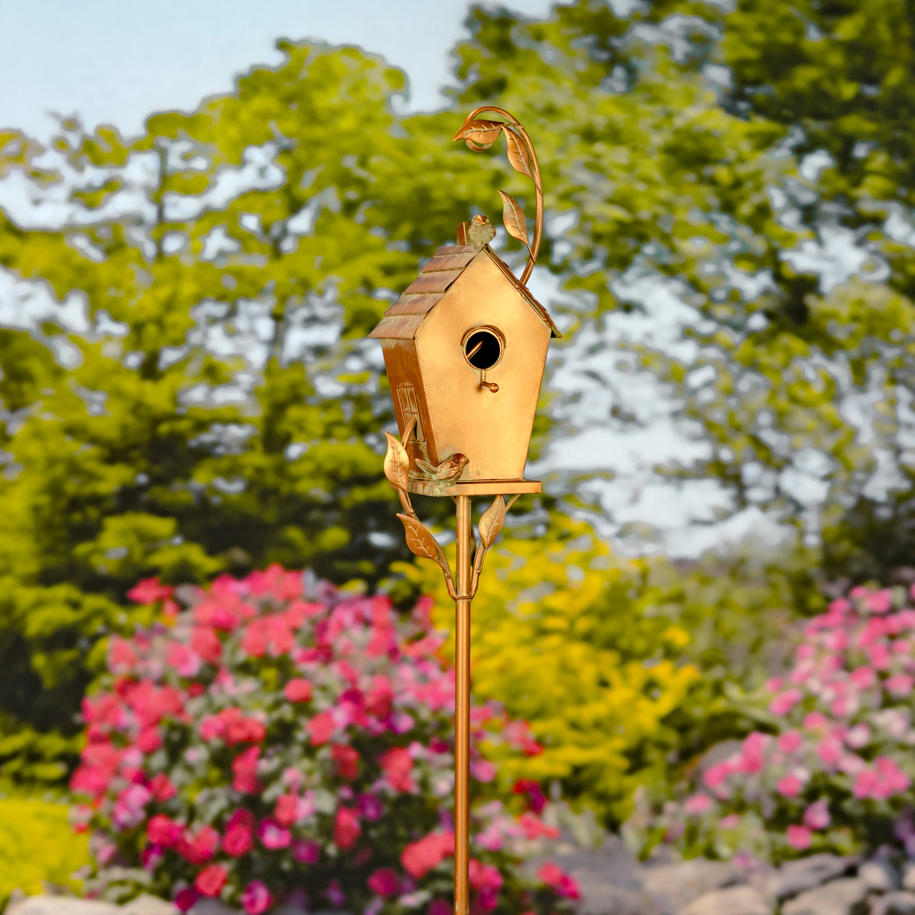 Decorative gold birdhouse on a stand with a garden background