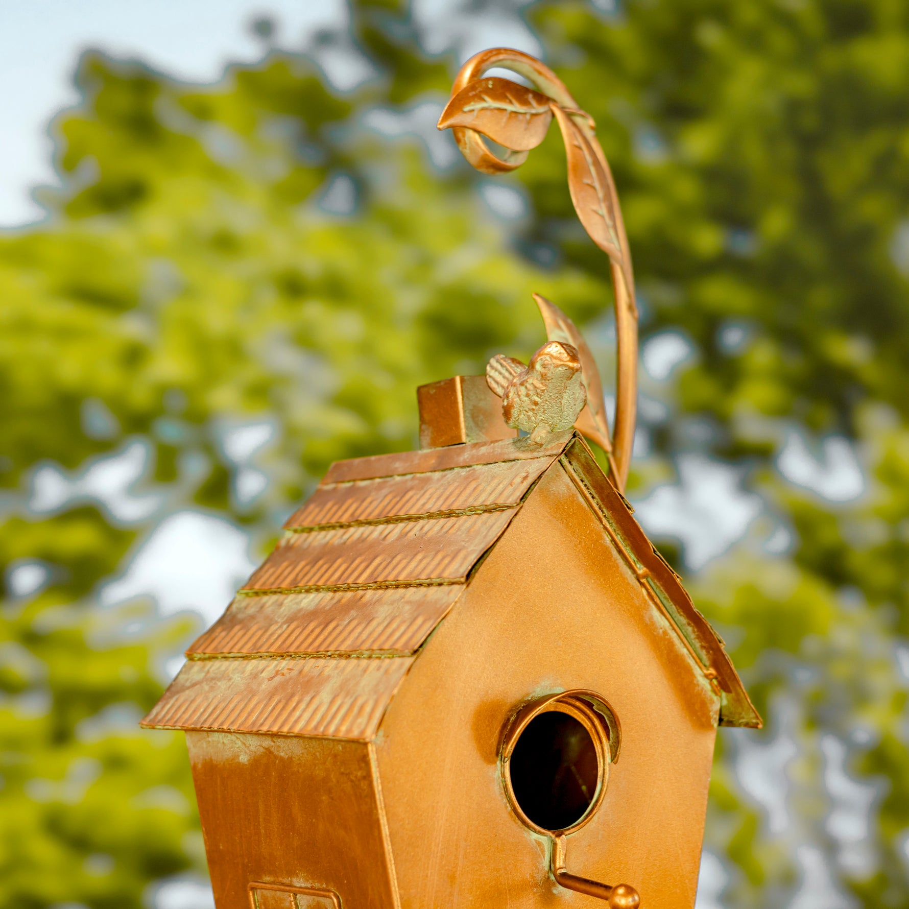 Decorative birdhouse with a leaf on top against a blurred green background
