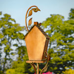 Decorative birdhouse with leaf design on a blurred natural background