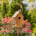 Decorative copper birdhouse on a stand with a garden background