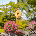 Decorative gold birdhouse on a stand with a garden background
