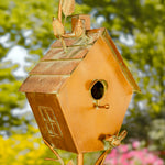 Copper birdhouse with decorative elements against a blurred natural background