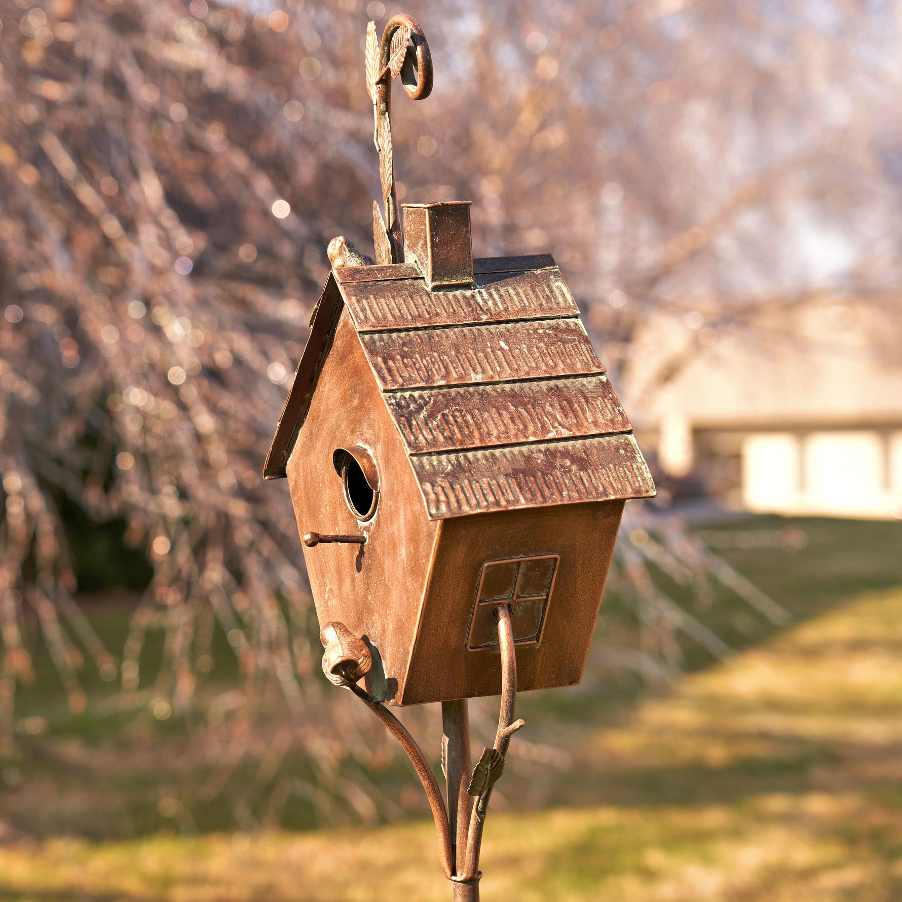 Wooden birdhouse on a stand with a blurred garden background