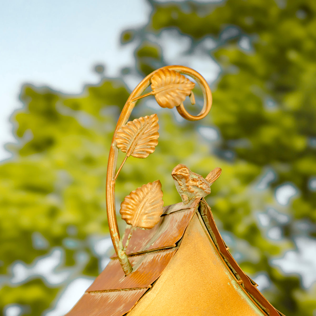 Decorative roof finial with leaf design against a blurred green background