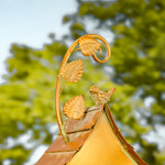 Decorative roof finial with leaf design against a blurred green background