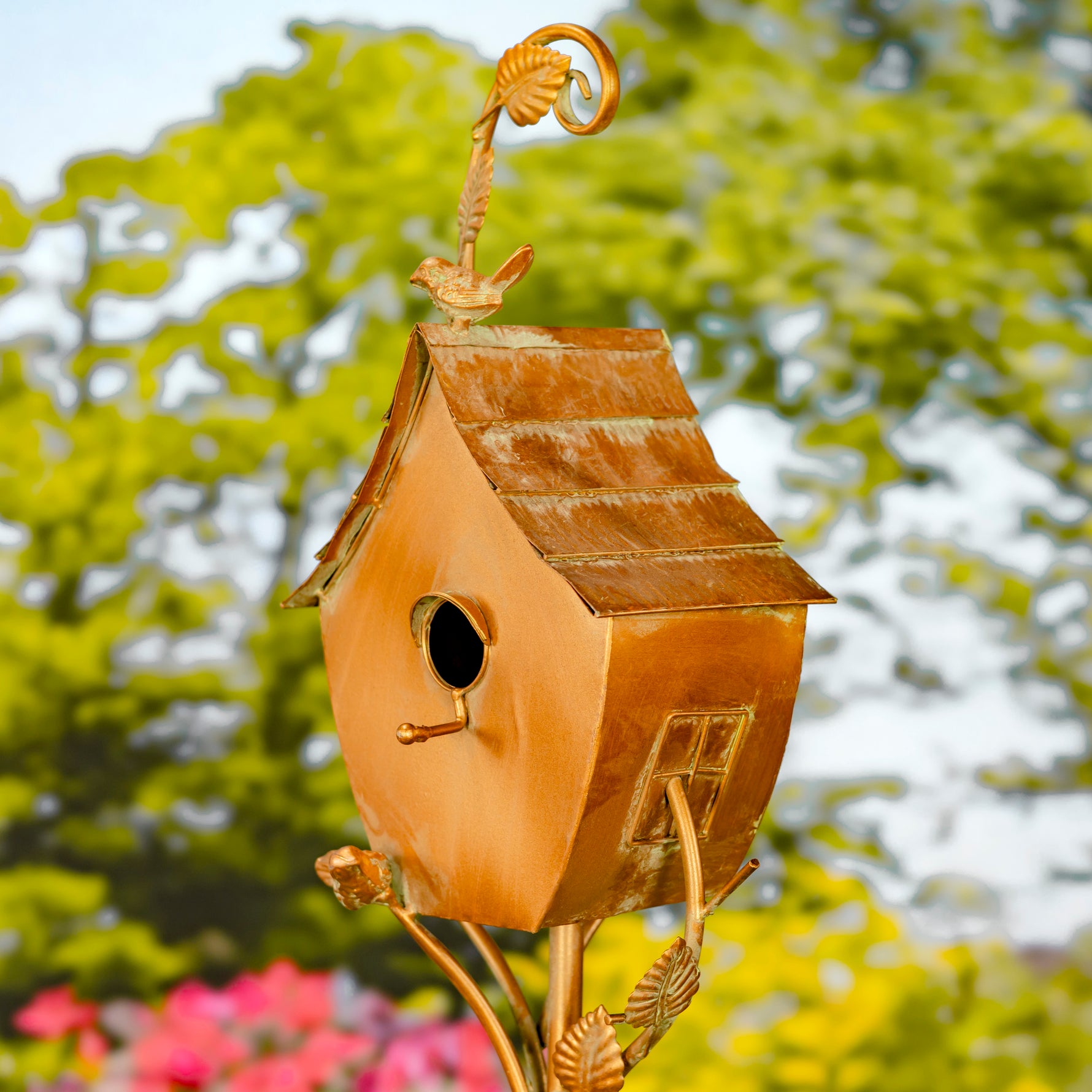 Decorative copper birdhouse with intricate details against a blurred natural background
