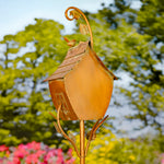 Decorative gold birdhouse on a stand with a blurred natural background
