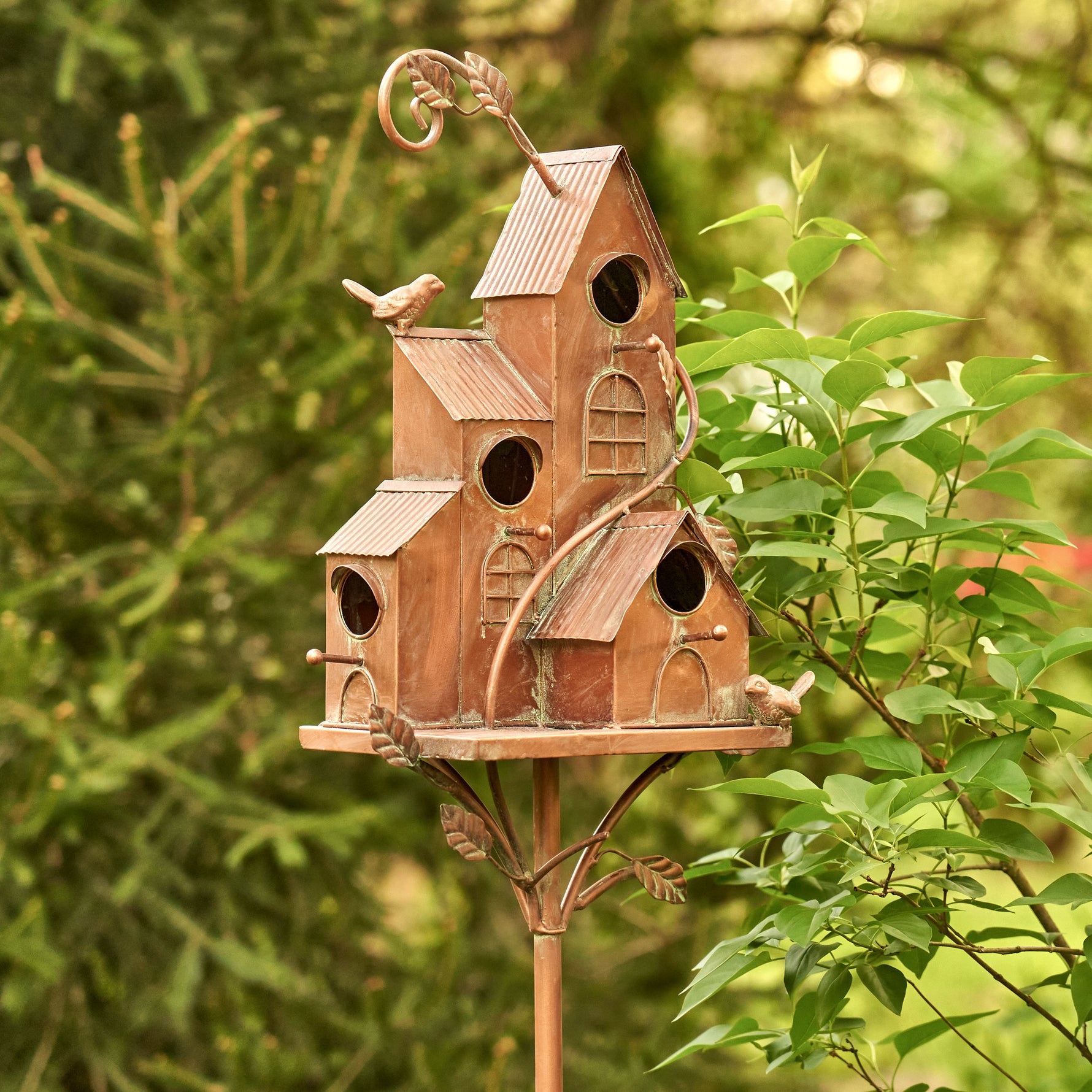Decorative birdhouse on a stand with a garden background
