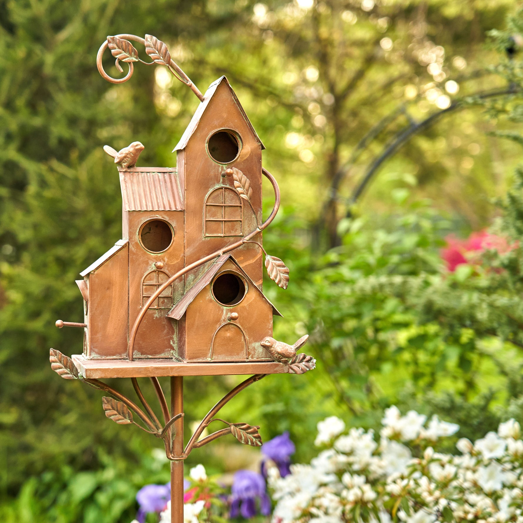 Decorative birdhouse on a stand with a garden background