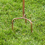 Rust-colored garden fork on green grass