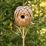 Decorative birdhouse shaped like a pine cone on a stand with a blurred green background