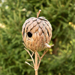 Decorative birdhouse shaped like a pine cone on a blurred green background