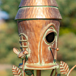 Decorative birdhouse with a rustic finish against a blurred natural background